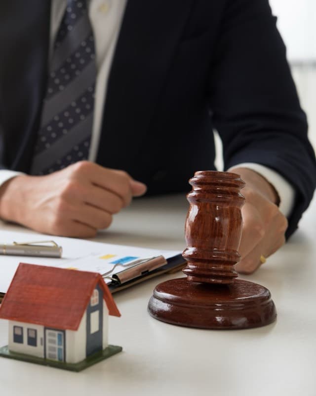 An auctioneer’s gavel beside a model house